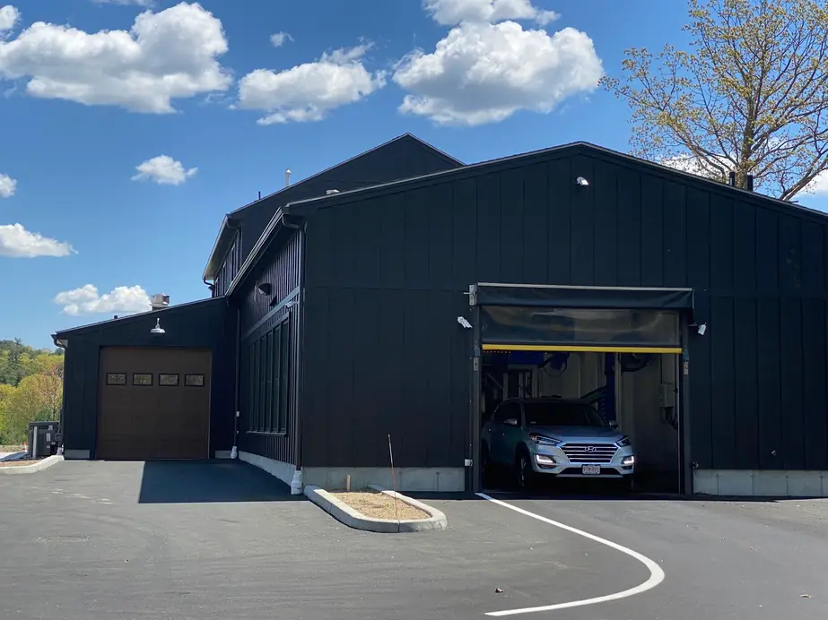 The side of the Mickey's barn and the tunnel exit door under a blue sky, with a car moving through the tunnel